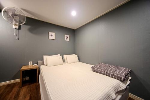 a small bedroom with a bed and a lamp at Welkin Hotel in Busan