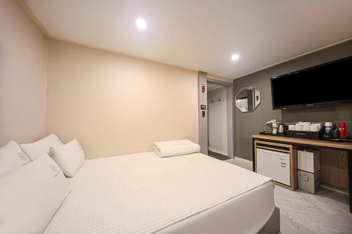 a hotel room with a bed and a flat screen tv at Welkin Hotel in Busan