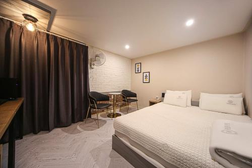 a bedroom with a bed and a table with chairs at Welkin Hotel in Busan