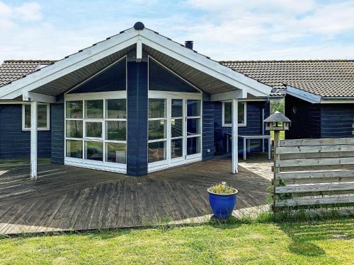 a blue house with a deck with a patio at 7 person holiday home in R dby in Rødby