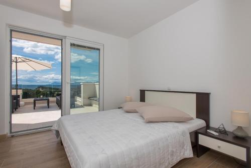 a white bedroom with a bed and a balcony at Apartments Villa Hadria in Makarska