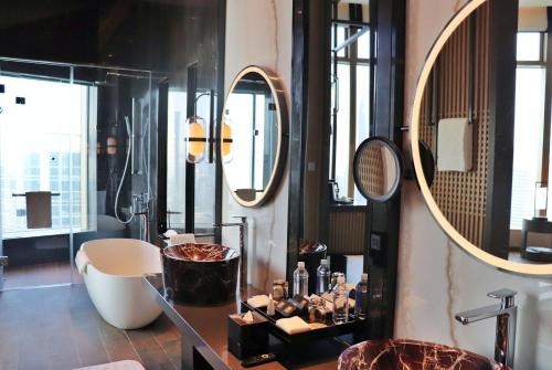 a bathroom with a tub and a sink and mirrors at Jumeirah Guangzhou - Complimentary Shuttle Bus to Canton Fair Complex in Guangzhou