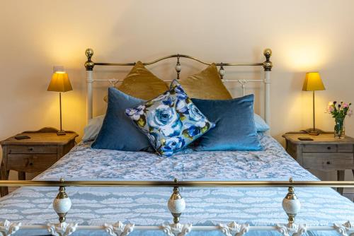 a bed with blue pillows on it with two lamps at Slades Farm in Edington
