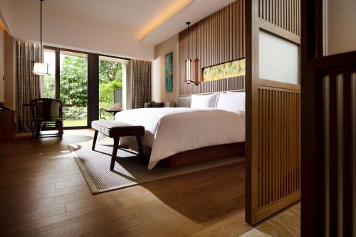 a bedroom with a white bed and a large window at New World Qingyuan Hotel -formerly KHOS QINGYUAN in Qingyuan