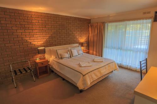 a bedroom with a bed and a brick wall at Mountain View Motor Inn & Holiday Lodges in Halls Gap