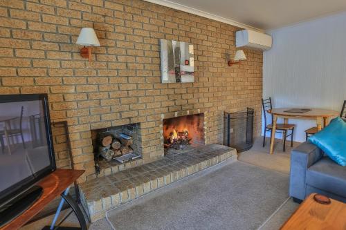 a brick wall with a fireplace in a living room at Mountain View Motor Inn & Holiday Lodges in Halls Gap