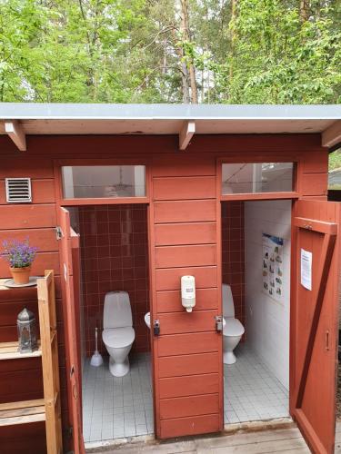 ein Badezimmer mit zwei WCs in einem roten Schuppen in der Unterkunft Siaröfortet Skärgårdskrog och Pensionat in Norra Ljustero