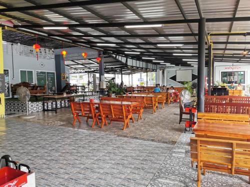 ein leeres Restaurant mit Holzstühlen und Tischen in der Unterkunft Chaiyai River Front Hotel in Sichon