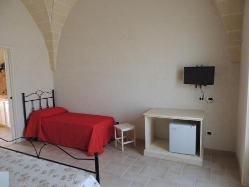 una camera con letto rosso e TV di Masseria Pasturi ad Avetrana
