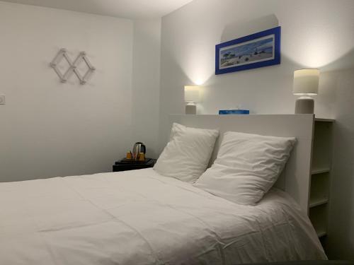 a white bed with white pillows in a bedroom at Le Melchior in Sainte-Terre