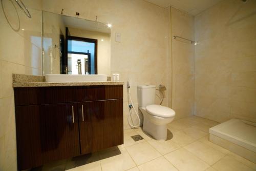 a bathroom with a toilet and a sink and a mirror at OYO Home 483 1BHK Tamcon DIP in Dubai