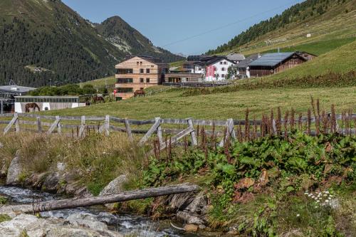 a wooden fence next to a river with houses at Hotel Jagdschloss Resort in Kühtai