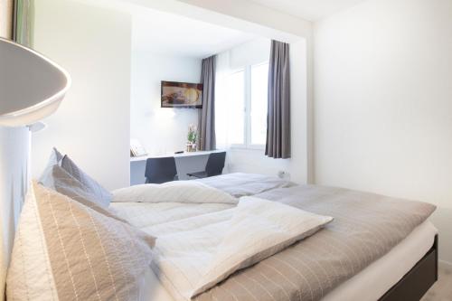 a white bedroom with a large bed with a window at Hotel Allegro Einsiedeln in Einsiedeln