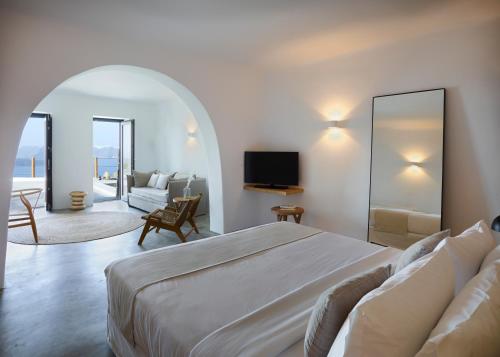 a bedroom with a bed and a living room at Melidonia Suites in Akrotiri