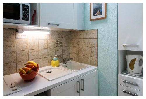 - une cuisine avec un évier et un bol de fruits sur le comptoir dans l'établissement Apartment Gîte Luvain Toulouse, à Toulouse