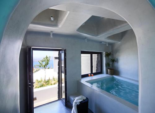a swimming pool in a house with an archway at Melidonia Suites in Akrotiri