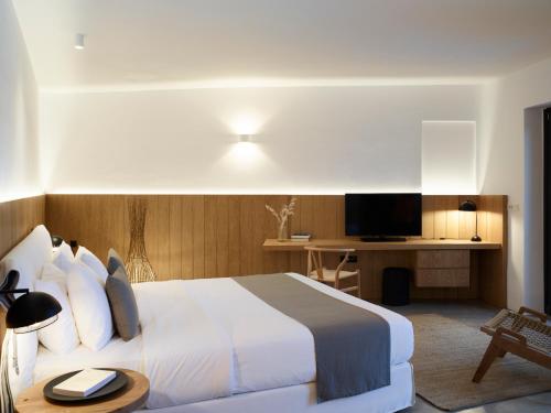 a hotel room with a bed and a television at Melidonia Suites in Akrotiri