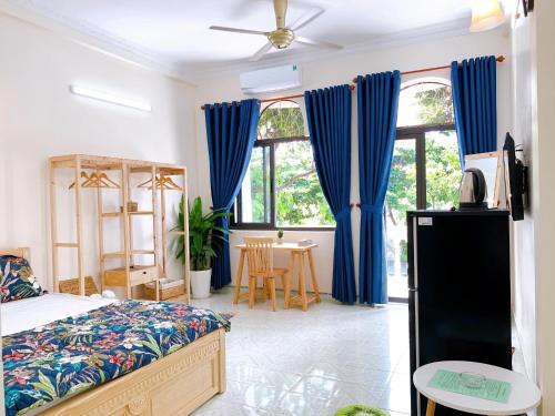 Xoài Xanh Hostel & Villa في فنغ تاو: غرفة نوم مع ستائر زرقاء وسرير وطاولة