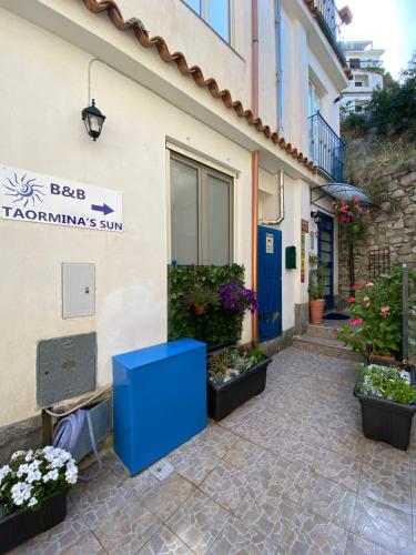 un edificio con una puerta azul y algunas plantas en Taormina’s Sun, en Taormina