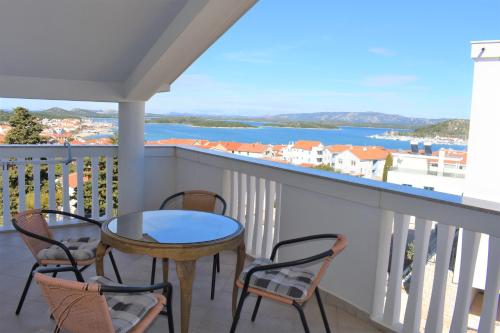 balcón con mesa, sillas y vistas al agua en Apartments Janja, en Murter