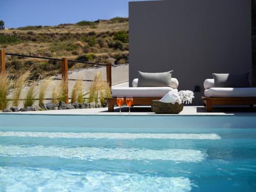 a view of a pool with two chairs at Melidonia Suites in Akrotiri