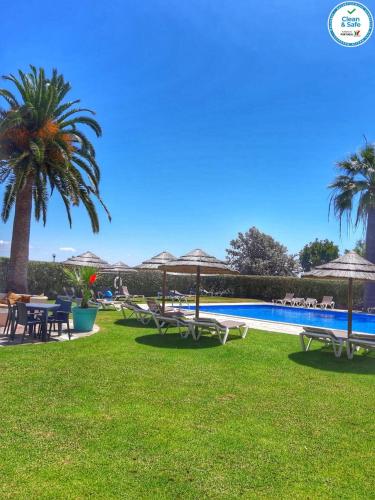 a pool with tables and umbrellas on the grass at Solar dos Vilarinhos - By bedzy in Albufeira