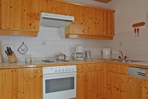 a kitchen with wooden cabinets and a white stove top oven at Ferienhaus Aurora in Kals am Großglockner
