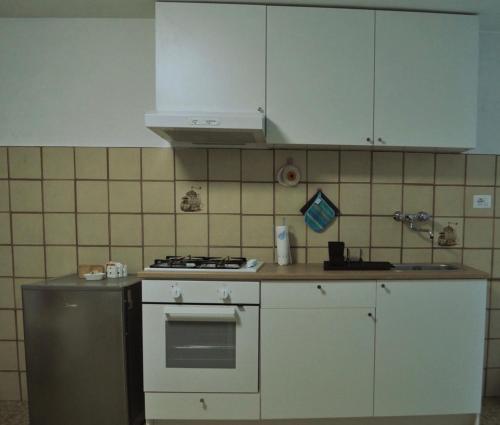 uma cozinha com um fogão e armários brancos em Bilocale a due passi dal Gran Paradiso em Locana