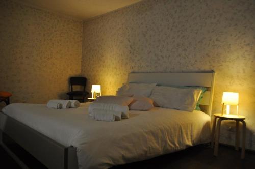 a bedroom with a large white bed with two lamps at Bilocale a due passi dal Gran Paradiso in Locana