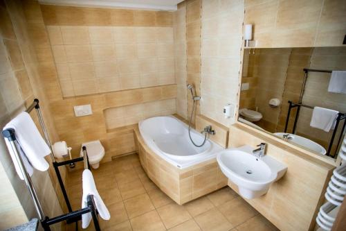 a bathroom with a tub and a toilet and a sink at Restauracja Sonata in Zwierzyniec