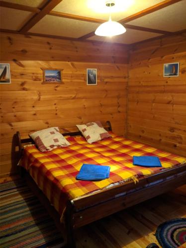 1 dormitorio con 1 cama en una habitación con paredes de madera en Лісова хатинка en Haivka