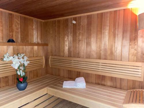 una sauna de madera con un jarrón de flores. en Hôtel Calme Des Pins & Spa en Les Sables-dʼOlonne