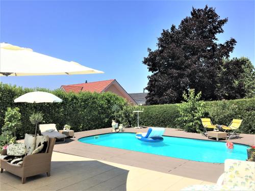 a swimming pool in a yard with chairs and an umbrella at Charming Villa with Private Swimmingpool in Attalens