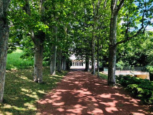 a tree lined path with a building in the distance at La Souveraine in Saint-Genis-Laval