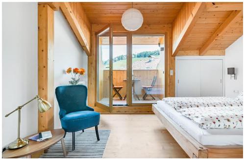 ein Schlafzimmer mit einem Bett und einem blauen Stuhl in der Unterkunft Lions Apartments in Völs am Schlern
