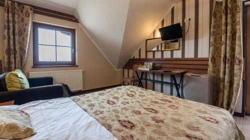 a bedroom with a bed and a desk and a window at Hotel Beskidzki Raj Medical SPA in Stryszawa