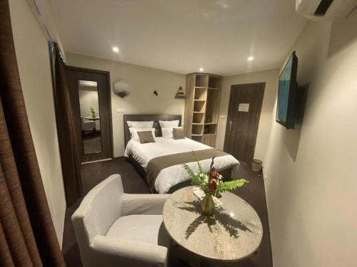 IvatoにあるFLY INN Madagascar HOTEL - Navette GRATUITE H24 - à 300m de l'Aéroport International Ivato-Antananarivoのベッドとテーブルとソファのあるホテルの部屋