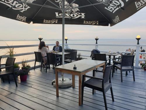people sitting at tables on a deck with the beach at Apartament "Złoty relaks" tuż przy plaży z balkonem z widokiem na Hel i hamakami in Puck