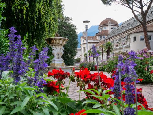 a garden with flowers in front of a fountain at Apartments Sabine G in Merano