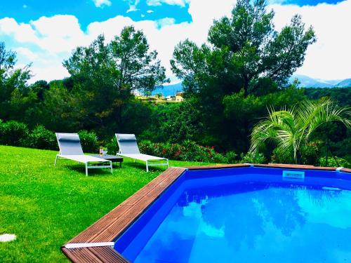 uma piscina com duas cadeiras brancas ao lado em La Gaude, villa 6 personnes-jardin-piscine-vue dégagée au calme em La Gaude