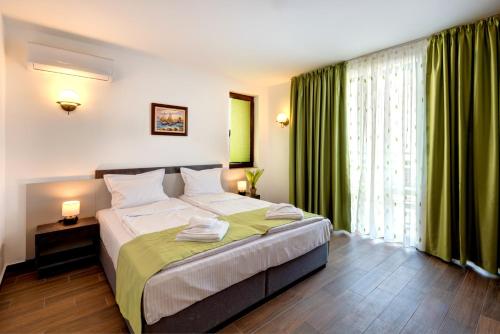 a bedroom with a large bed with green curtains at Panorama Blue Family Hotel and Free parking in Nesebar
