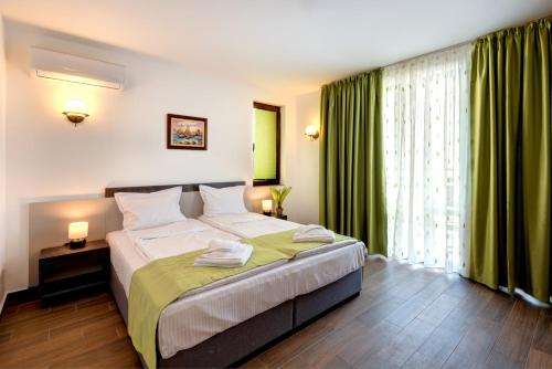 a bedroom with a large bed with green curtains at Panorama Blue Family Hotel in Nesebar