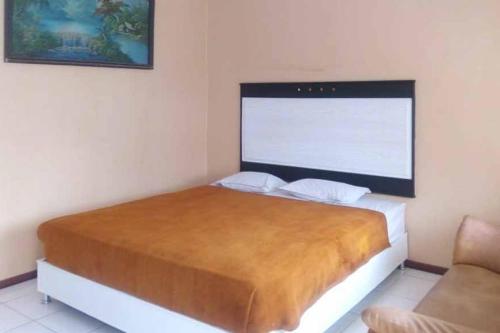 a bedroom with a bed with a large headboard at RedDoorz Syariah @ Hotel Kencana Tasikmalaya in Tasikmalaya
