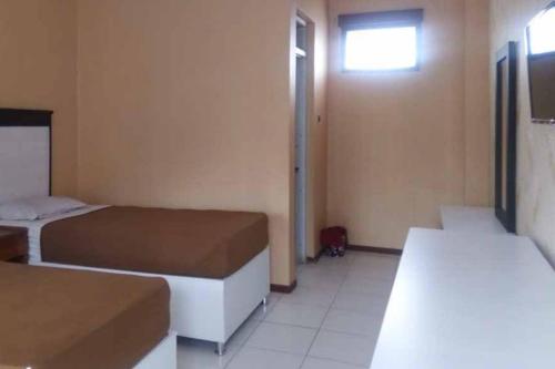 a small room with two beds and a window at RedDoorz Syariah @ Hotel Kencana Tasikmalaya in Tasikmalaya