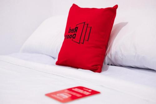 a red pillow sitting on top of a bed with a redlip at RedDoorz Syariah @ Hotel Kencana Tasikmalaya in Tasikmalaya