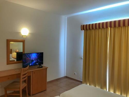 a hotel room with a desk with a television and a bed at Luz Bay Hotel in Luz