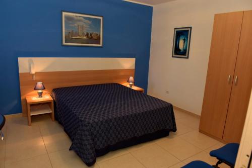 1 dormitorio con cama y pared azul en Bilocali Civico16, en Porto Cesareo