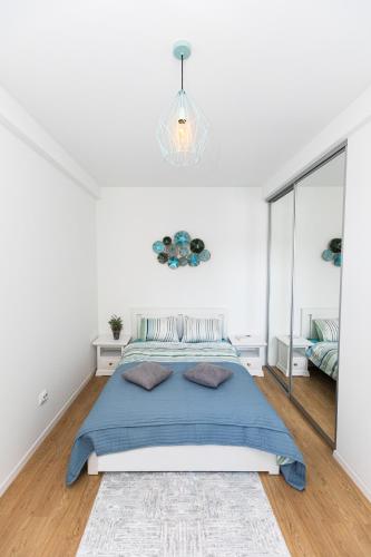 a bedroom with a blue bed and a chandelier at Colorful & Cozy Condo in Cluj-Napoca