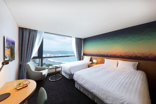 a hotel room with two beds and a large window at Mercure Ambassador Ulsan in Ulsan