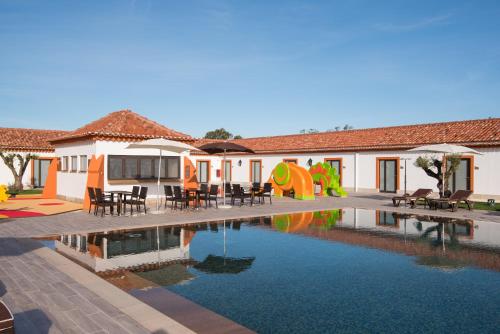 um resort com uma piscina com mesas e cadeiras em Vila Gale Collection Alter Real - Resort Equestre, Conference & Spa em Alter do Chão